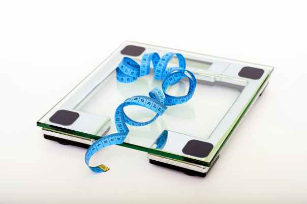 blue tape measuring on clear glass square weighing scale