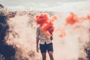 person standing while face covering with smoke